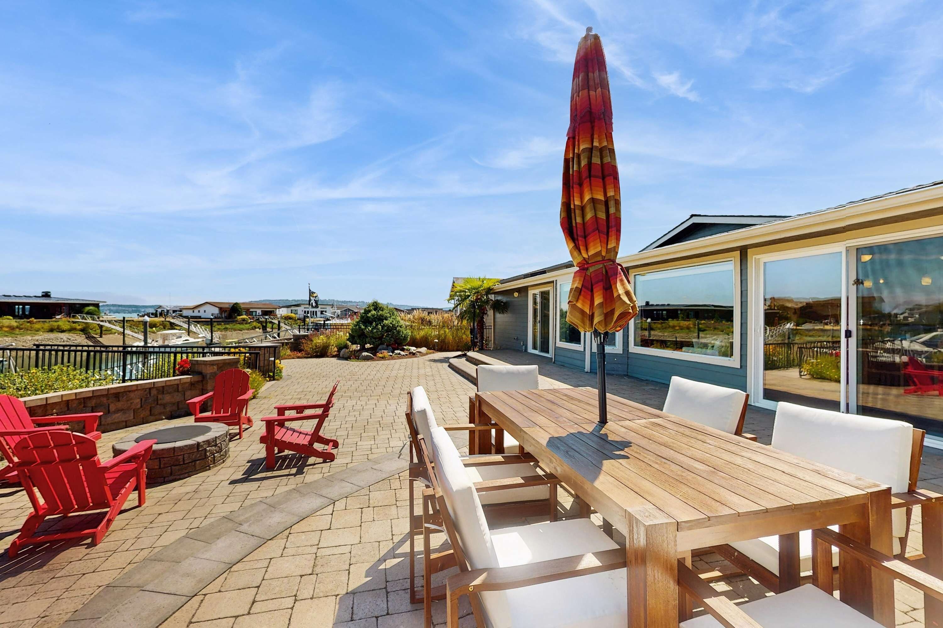 An outdoor patio with wooden furniture, a large umbrella, and a view of the city.
