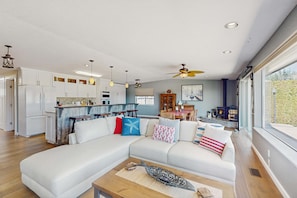 A modern living room with a sectional sofa, a wooden coffee table, and a view of the kitchen and dining area. - Stunning Waterfront Home with Private Dock and Sauna in Oak Harbor (Oak Harbor)