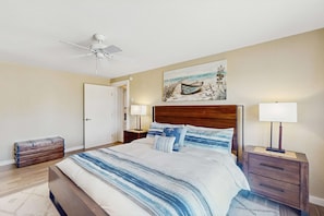 A bedroom with a bed, two bedside tables, a ceiling fan, a painting, and a wooden chest of drawers. - Stunning Waterfront Home with Private Dock and Sauna in Oak Harbor (Oak Harbor)