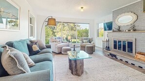 Un salon spacieux avec une cheminée, une grande fenêtre et un coin salon confortable.