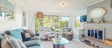 A spacious living room with a fireplace, a large window, and a cozy seating area.
