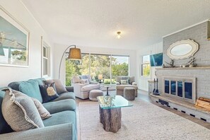A spacious living room with a fireplace, a large window, and a cozy seating area.