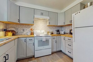 A modern kitchen with light grey cabinets, a white stove, and a stainless steel refrigerator.