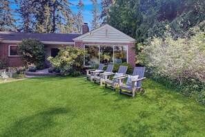 A house with a covered patio area, a lawn, and outdoor seating.