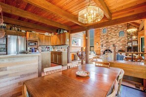 Eine rustikale Küche mit Holzschnitzschränken, einer zentralen Kochinsel und einem Essbereich mit einem Holztisch.