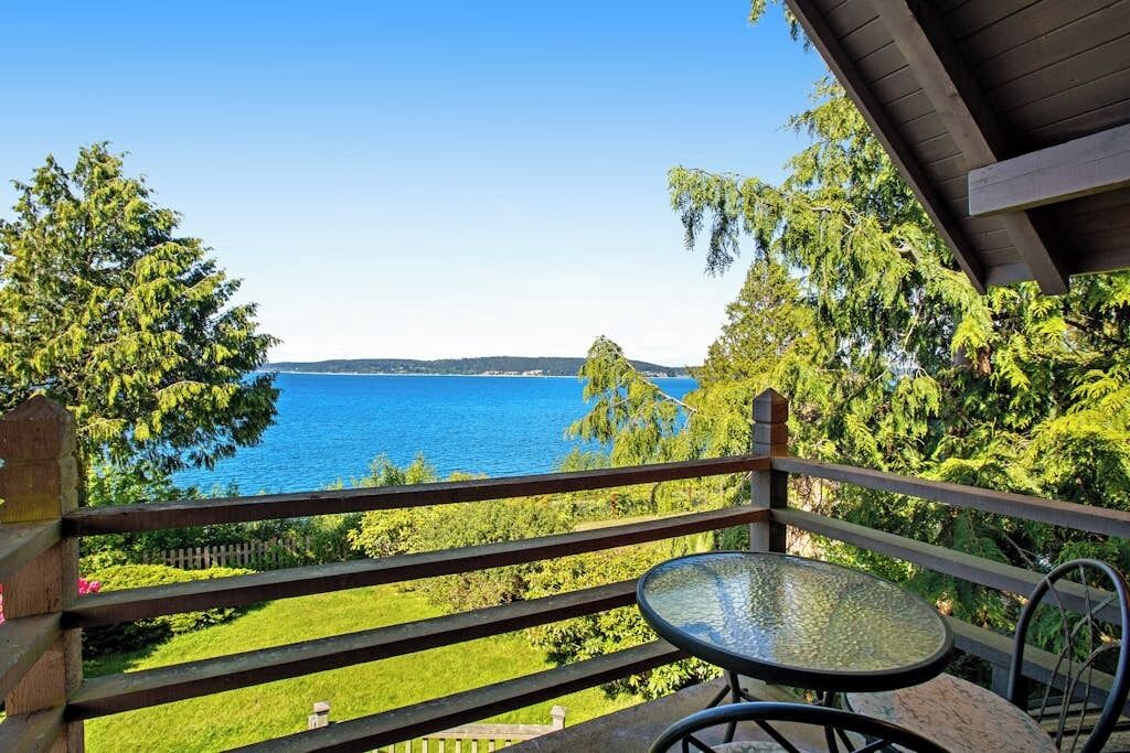 A balcony with a clear view of the sea, surrounded by greenery.