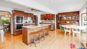 A modern kitchen with wooden cabinets, stainless steel appliances, and a central island with stools. - 4 BR Pet Friendly Waterfront Home with Game Room (Clinton)