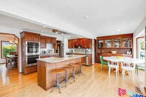 A modern kitchen with wooden cabinets, stainless steel appliances, and a central island with stools.