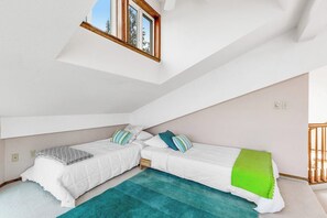 A bedroom with two beds, a skylight, and a view of the outdoors.