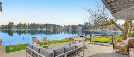Une terrasse au bord du lac, aménagée avec du mobilier d’extérieur et un barbecue, offrant une vue sur le lac.