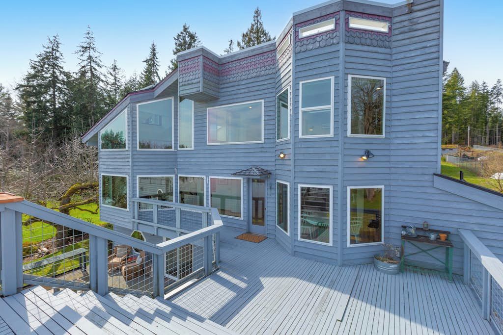 A multi-level wooden house with large windows and a deck.