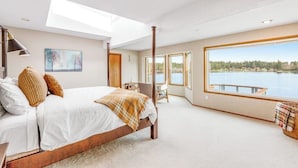 A bedroom with a large bed, a skylight, a view of a lake, and a window with a view of a dock. - 4 BR Pet Friendly Waterfront Home with Game Room (Clinton)