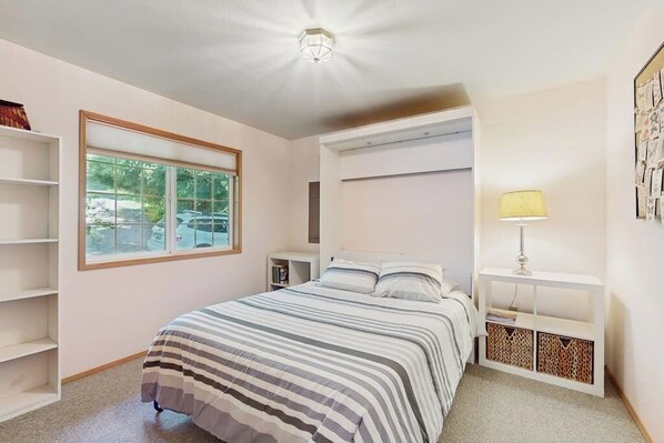 A bedroom with a bed, a window, a bedside table, and a lamp. - Stunning Waterfront Home on Lopez Island with Private Beach Access and Fire Pit (Lopez Island)