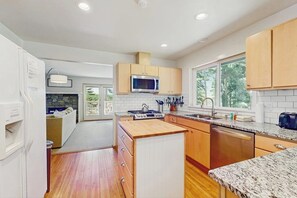 A modern kitchen with wooden cabinets, a built-in microwave, and a granite countertop. - Stunning Waterfront Home on Lopez Island with Private Beach Access and Fire Pit (Lopez Island)