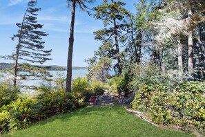 A garden with a lawn, trees, and a view of a lake. - Stunning Waterfront Home on Lopez Island with Private Beach Access and Fire Pit (Lopez Island)