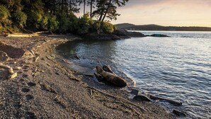 Rantaviiva, jossa on kivikkoista maastoa, puita ja tyyni vesi.