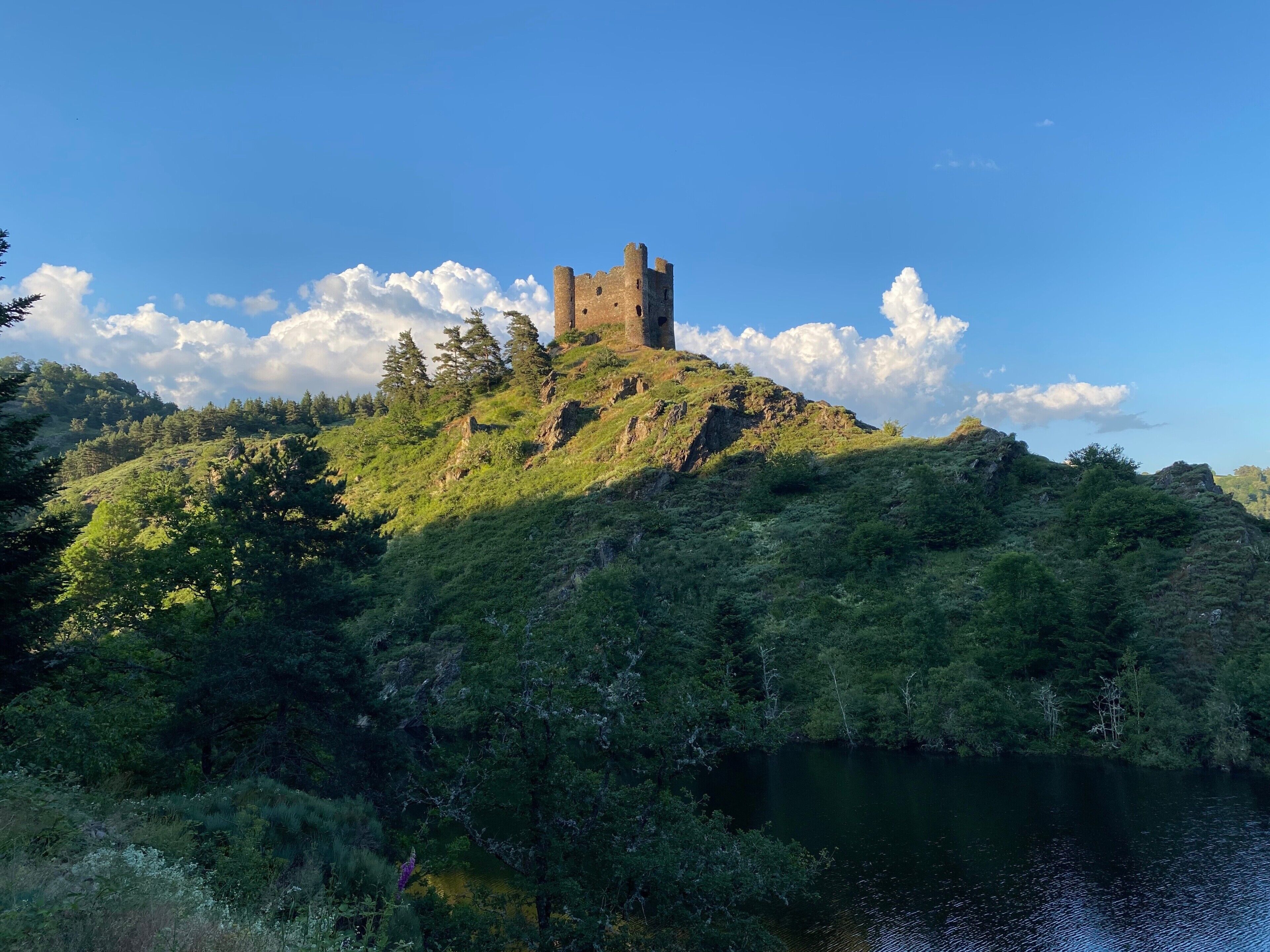 A castle on a hill with a lake in the foreground.