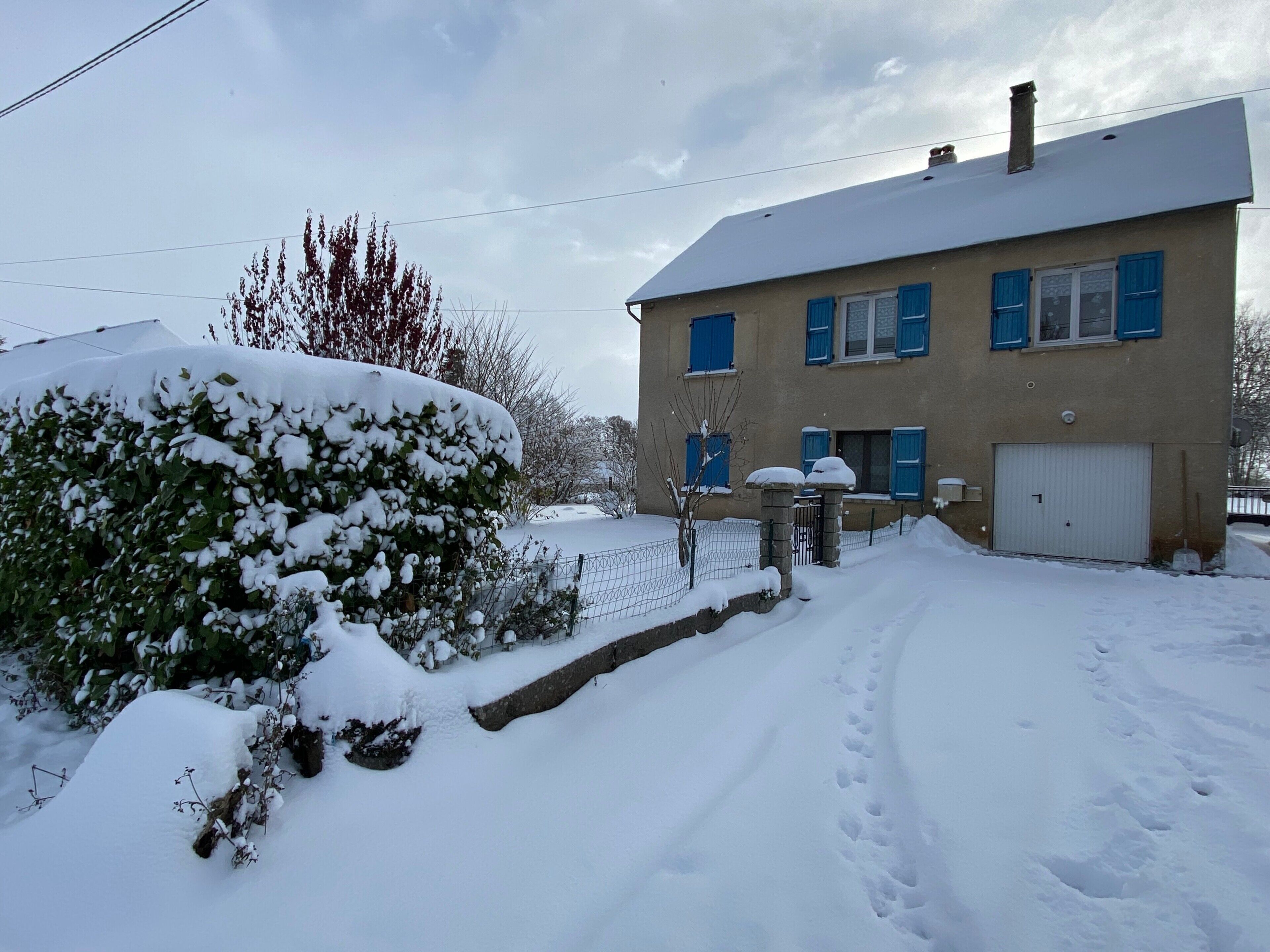 A two-story house with a snow-covered roof and a garage.