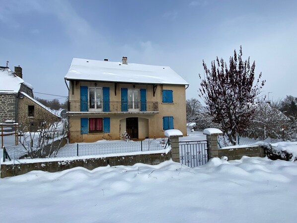 A two-story house with a balcony, surrounded by snow.