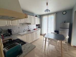 Una cocina moderna con armarios blancos, microondas, lavamanos y comedor con mesa y sillas.