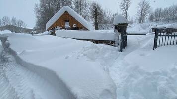 Un paysage enneigé avec une structure en bois, peut-être une grange, et un portail en métal.