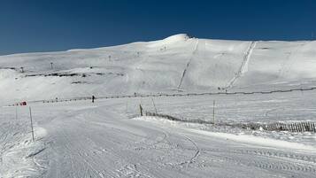 Een piste bedekt met sneeuw, met uitgestippelde loipes en een heldere lucht.