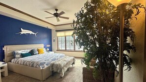 A bedroom with a bed, a ceiling fan, a large potted plant, and a window with blinds. - Vesper Bleu  2 Kings + EV Charger (Coeur d'Alene)
