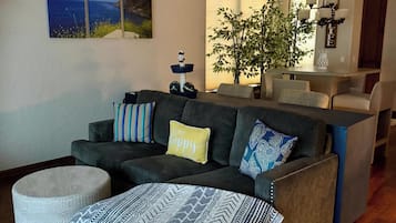 A modern living room with a sectional sofa, ottoman, and a dining area with a table and chairs.