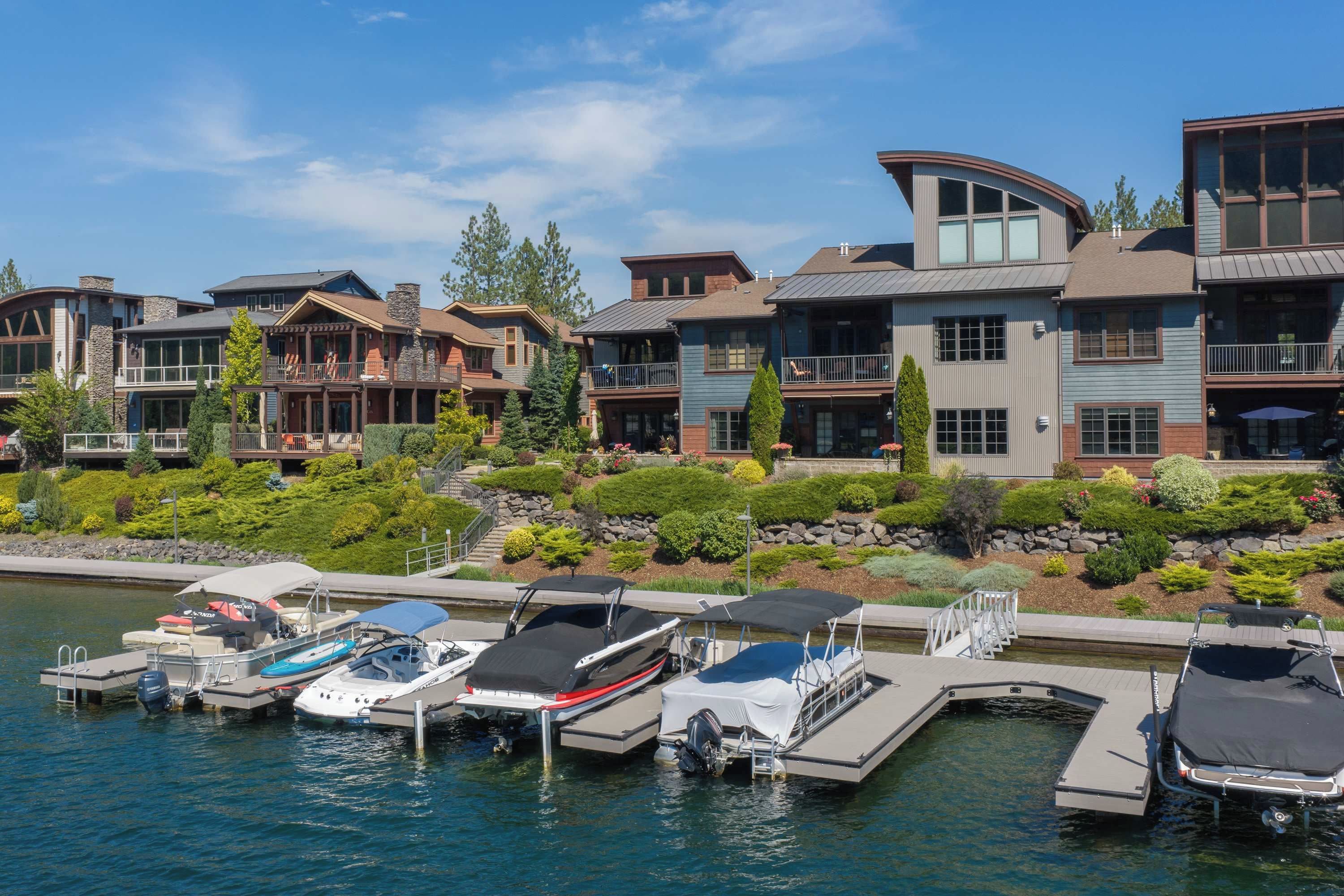 A waterfront property with multiple boats docked, a dock with a covered area, and a row of houses with balconies.