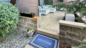 A residential property with a welcome mat, outdoor seating area, and a stone wall. - Vesper Bleu  2 Kings + EV Charger (Coeur d'Alene)