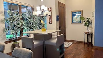 A dining area with a table and chairs, a chandelier, and potted plants.