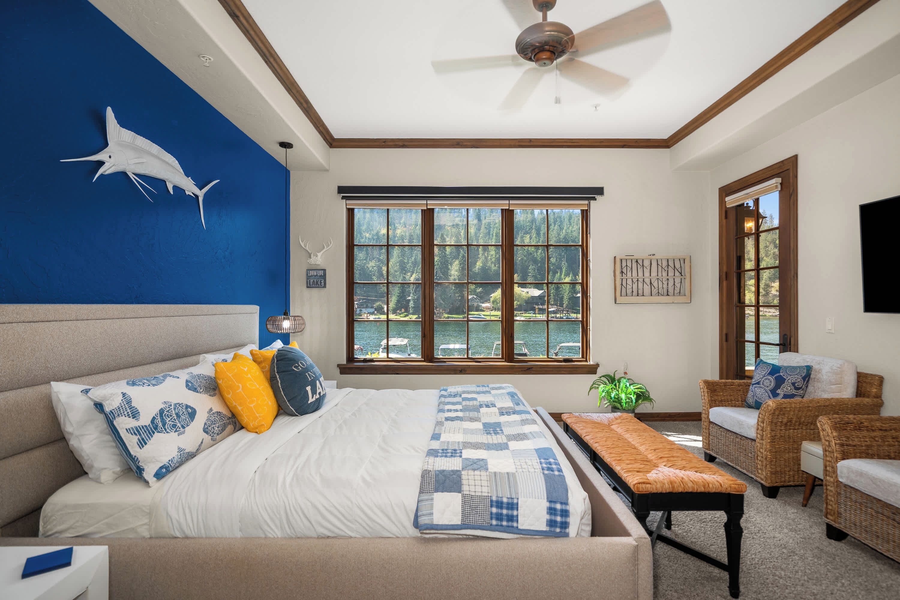 Bright coastal-inspired bedroom with a comfortable bed and large windows overlooking the trees.