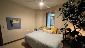 A bedroom with a bed, a ceiling fan, a window, and a plant. - Vesper Bleu  2 Kings + EV Charger (Coeur d'Alene)