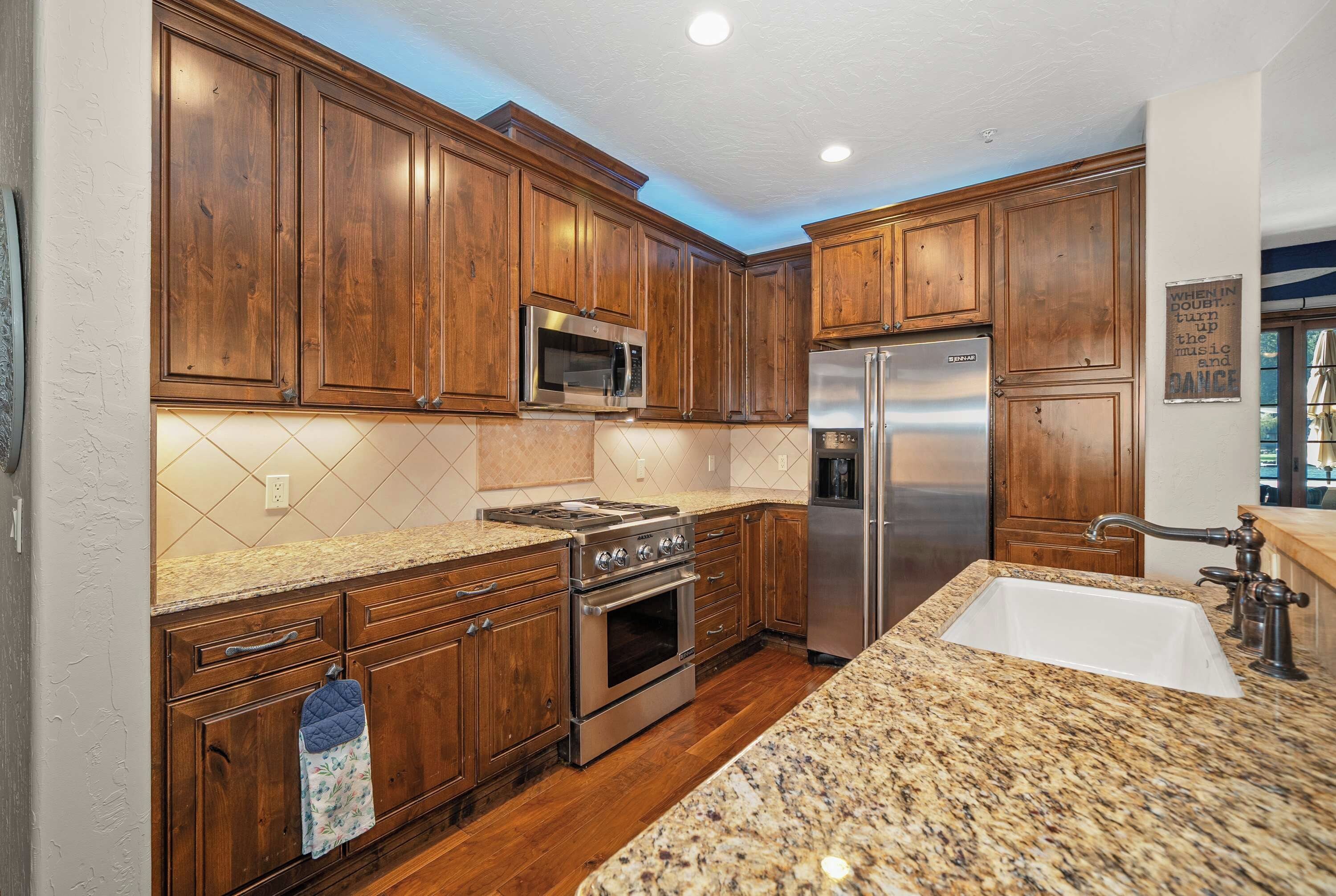 A kitchen with wooden cabinets, stainless steel appliances, a granite countertop, and a built-in oven.