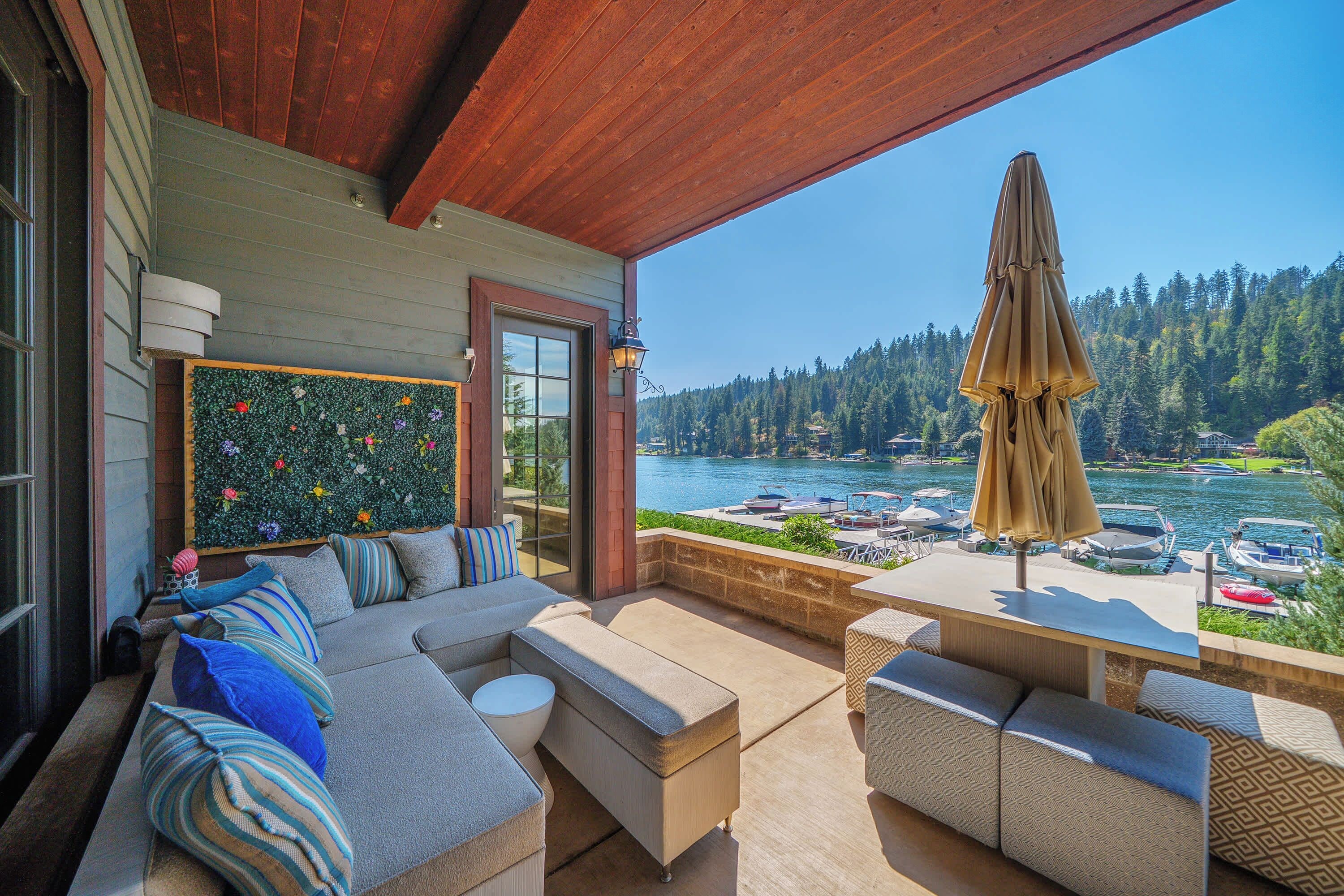 Covered lakeside patio with comfortable lounge seating, scenic water views, and a peaceful setting for relaxing outdoors.
