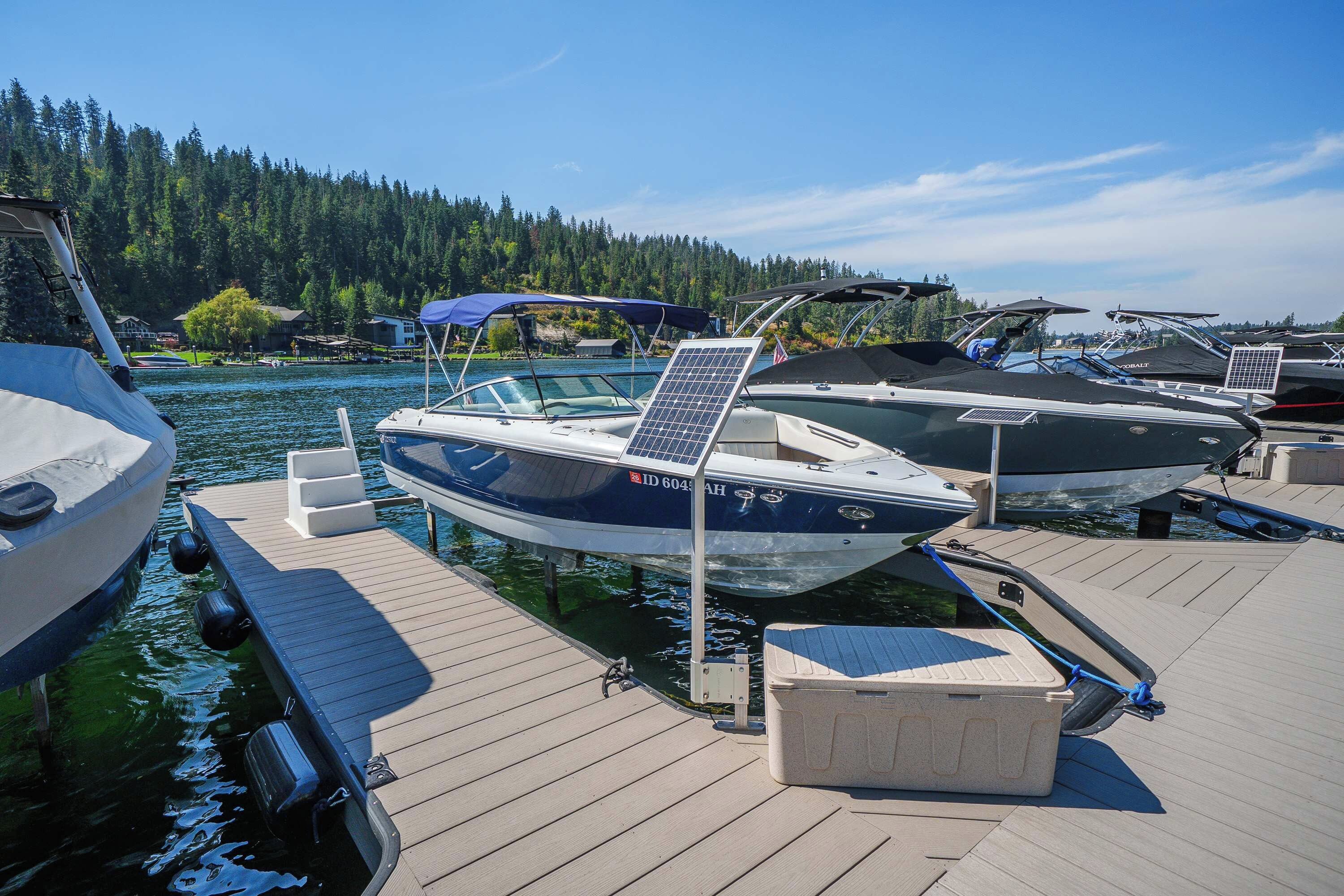 A marina with boats docked on wooden piers, surrounded by a forested landscape.