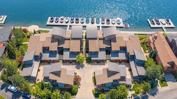 A residential area with a marina, featuring houses with sloped roofs, a clear view of the water, and a parking area.