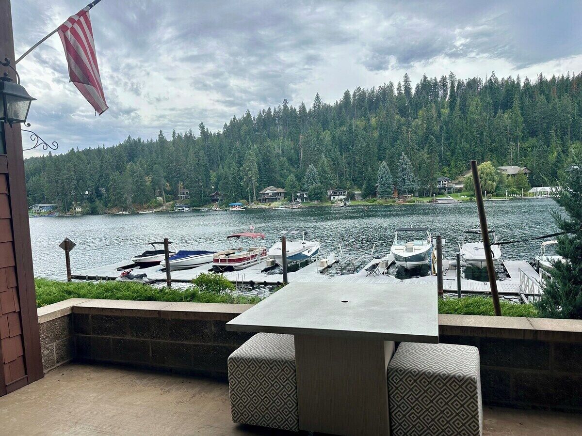 Une terrasse avec une table et des chaises donnant sur une marina où sont amarrés des bateaux.