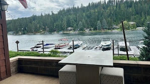 A patio with a table and chairs overlooking a marina with boats docked. - Vesper Bleu  2 Kings + EV Charger (Coeur d'Alene)