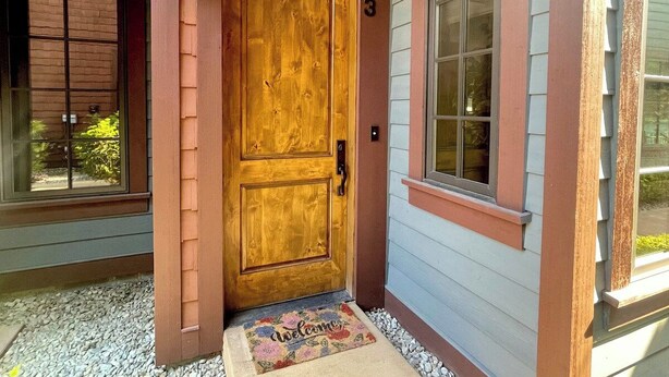 A wooden front door with a number '103' above it, a welcome mat, and a window to the right. - Vesper Bleu  2 Kings + EV Charger (Coeur d'Alene)