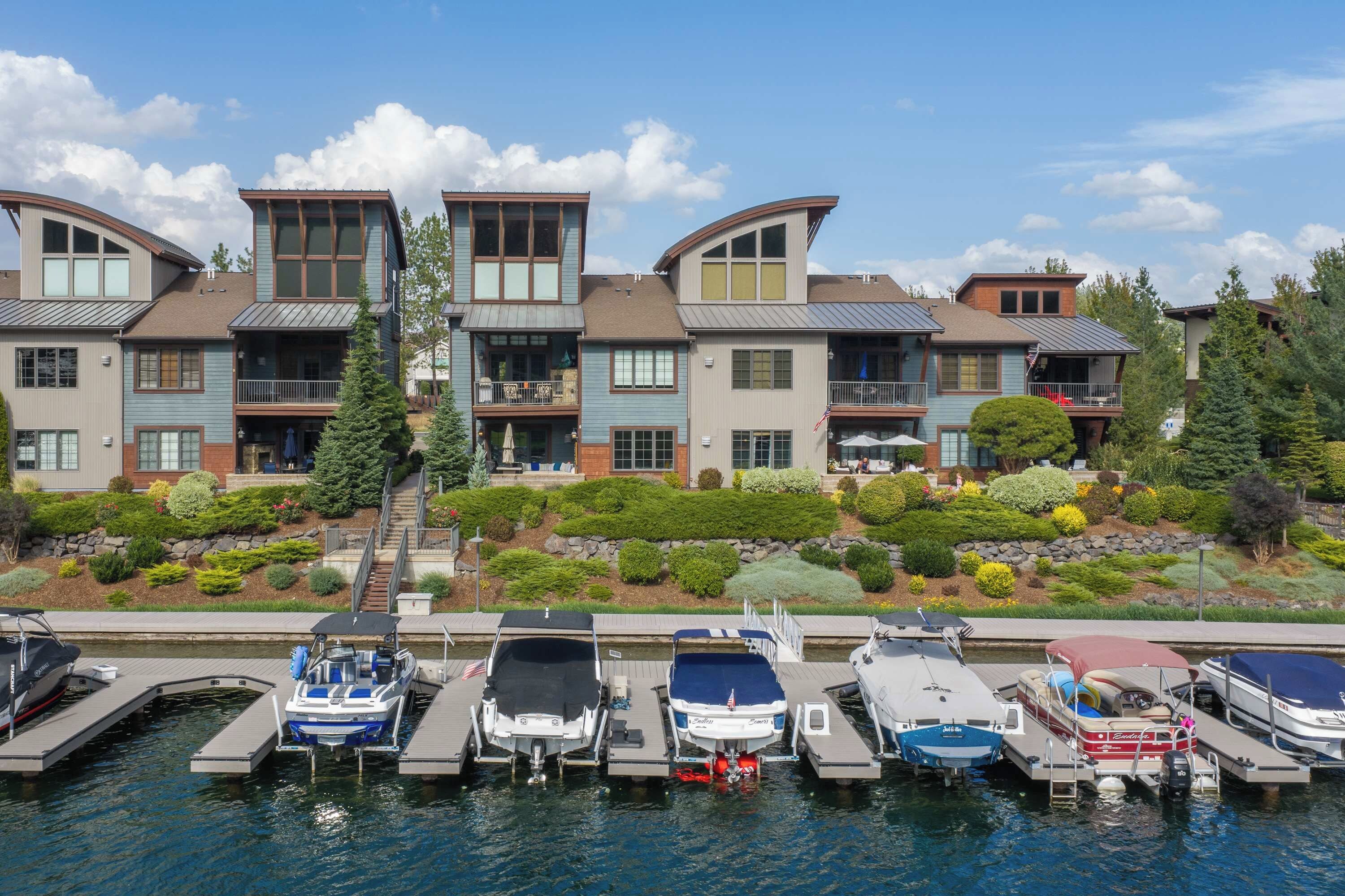 A waterfront property with multiple boats docked, a well-maintained garden, and a multi-story building with balconies.