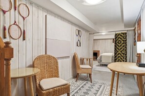 Ein Hotelzimmer mit einem Bett, zwei Korbstühlen, einem kleinen Tisch und Tennisracket an der Wand.
