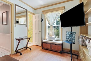 A room with a desk, a television on a stand, a window with curtains, and a door. - 
The Bishop Retreat  5BR, Tennis Court & Yard (Alexandria)