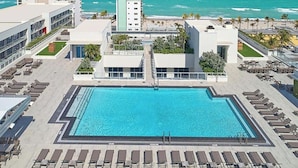 Ein Pool auf dem Dach mit Liegestühlen, Blick auf den Ozean und ein Gebäude im modernen Stil.