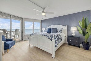A bedroom with a bed, a chair, a nightstand, a lamp, and a potted plant. - New Listing! Updated Oceanfront 2/2 | Heated Pool & Garage Parking (Ormond Beach)