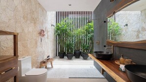 A modern bathroom with a stone wall, a wooden vanity, a large black basin, and several potted plants. - "Rana Curiosa" @BlueDeerTulum - 4 Bed+4.5 Bath LUX Villa - Pool, Jacuzzi, Staff (Tulum)