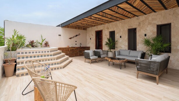 A covered outdoor patio with a stone wall, a wooden staircase, wicker furniture, and potted plants. - "Rana Curiosa" @BlueDeerTulum - 4 Bed+4.5 Bath LUX Villa - Pool, Jacuzzi, Staff (Tulum)