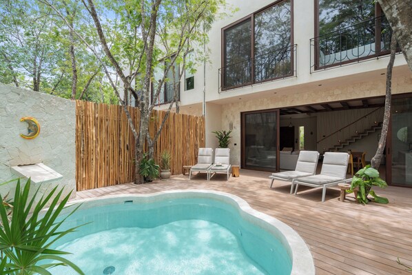 Una casa moderna amb piscina, zona d'estar a l'exterior i escala que condueix a un segon pis.