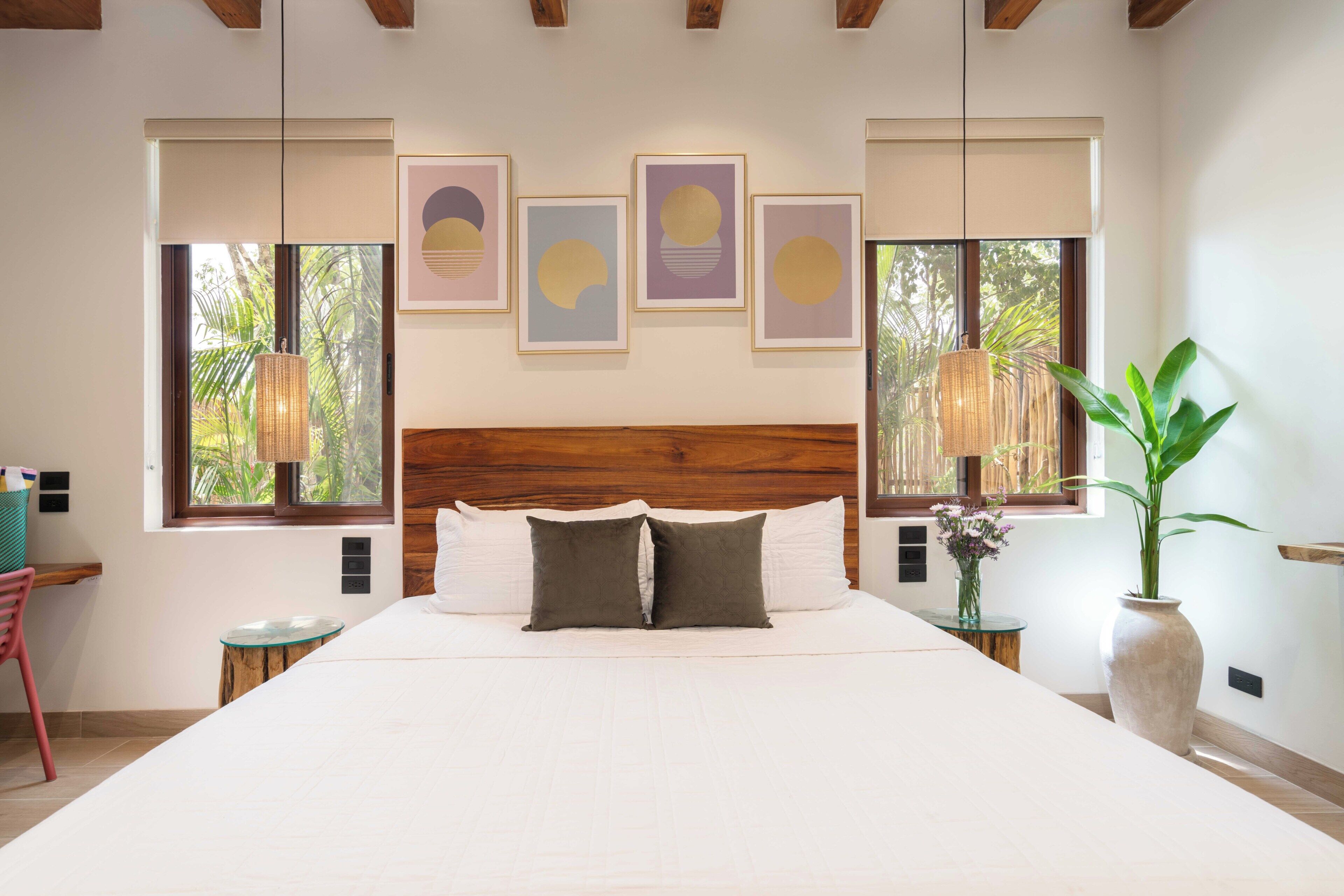 Quarto com uma cama grande, cabeceira de madeira e obras de arte na parede.