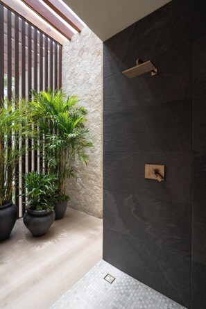 A modern bathroom with a stone wall, a wooden shower enclosure, and potted plants. - LUX 4BR/4.5 Bath Villa - Private Pool & Hot Jacuzzi +Staff - BLUE DEER TULUM (Tulum)